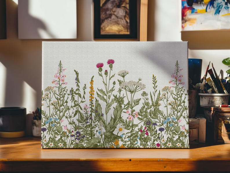 May include: A white canvas print featuring a floral design with a variety of wildflowers in shades of pink, purple, blue, yellow, and green. The flowers are arranged in a horizontal row across the canvas.