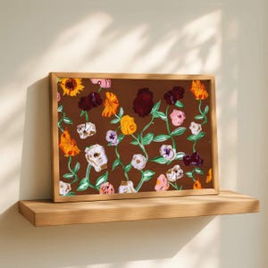 Puede incluir: Pintura floral enmarcada con fondo marrón, que muestra flores coloridas en tonos amarillos, naranjas, rosas, blancos y burdeos. Las flores están conectadas por tallos verdes. El marco es de madera marrón claro.
