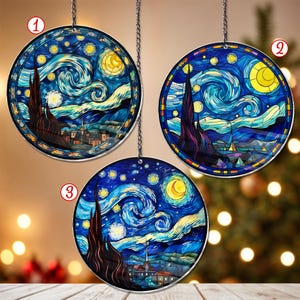 Könnte beinhalten: Drei runde Buntglas-Anhänger mit einer Reproduktion von Vincent van Goghs 'Sternennacht'. Die Anhänger hängen an Ketten vor dem Hintergrund eines Weihnachtsbaums.