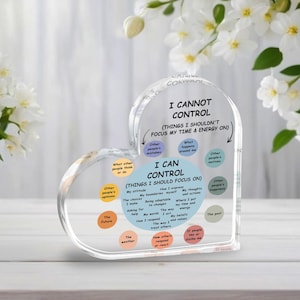 May include: A clear, heart-shaped acrylic desk decor piece with the text "I Cannot Control" and "I Can Control." The design includes a list of things one can and cannot control, with a floral background.
