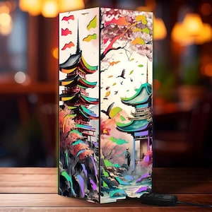 May include: A rectangular lamp with a Japanese pagoda design. The lamp features colorful illustrations of pagodas, trees, and birds. The lamp is made of wood and has a black power cord.