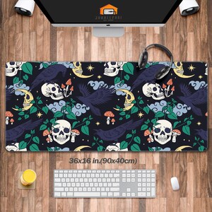 May include: A black desk mat with a repeating pattern of skulls, ravens, mushrooms, and crescent moons. The mat measures 36 x 16 inches. The design includes green vines and yellow stars. The mat is designed for a computer setup.