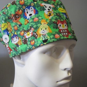 May include: Green scrub hat with a pattern of Animal Crossing characters, including Tom Nook, Isabelle, and K.K. Slider.