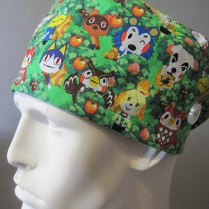 May include: Green scrub hat with a colorful print of animal characters from the video game Animal Crossing. The hat has a button on the side.