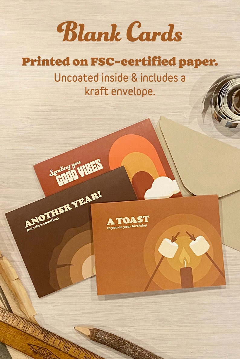 May include: Four blank greeting cards with different designs. The cards feature a rainbow, a campfire, and the text "Sending you good vibes", "Another year! But who's counting", and "A toast to you on your birthday".