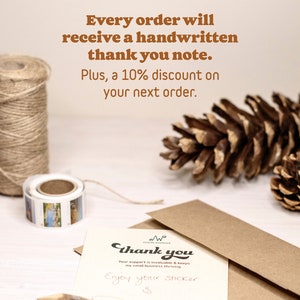May include: A handwritten thank you note on a brown envelope with the text "Thank you" and "Your support is invaluable & keeps my small business thriving" and "Enjoy your sticker". The note is surrounded by twine, a pine cone, and a roll of washi tape.