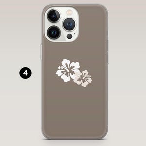 May include: A phone case with a taupe background and a white floral design. The case has a clear border and a camera cutout. The floral design features two white hibiscus flowers.