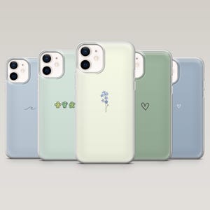 May include: Five phone cases in pastel shades are displayed. Each case has a minimalist design, such as a wave, cacti, a flower, a heart, and a small heart. The cases are made of a clear material.