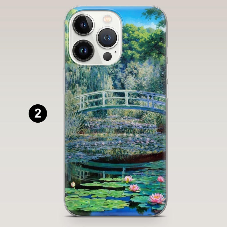 May include: A phone case with a colorful image of a bridge over a pond with lily pads and flowers. The phone case has a clear back and a white front with a camera lens.