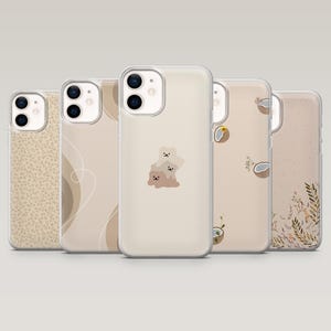 May include: Five clear smartphone cases arranged in a row, each featuring distinct designs: a small floral pattern, abstract white lines, a central stack of three small cartoon bears, scattered coconut halves, and a cluster of brown botanical leaves.