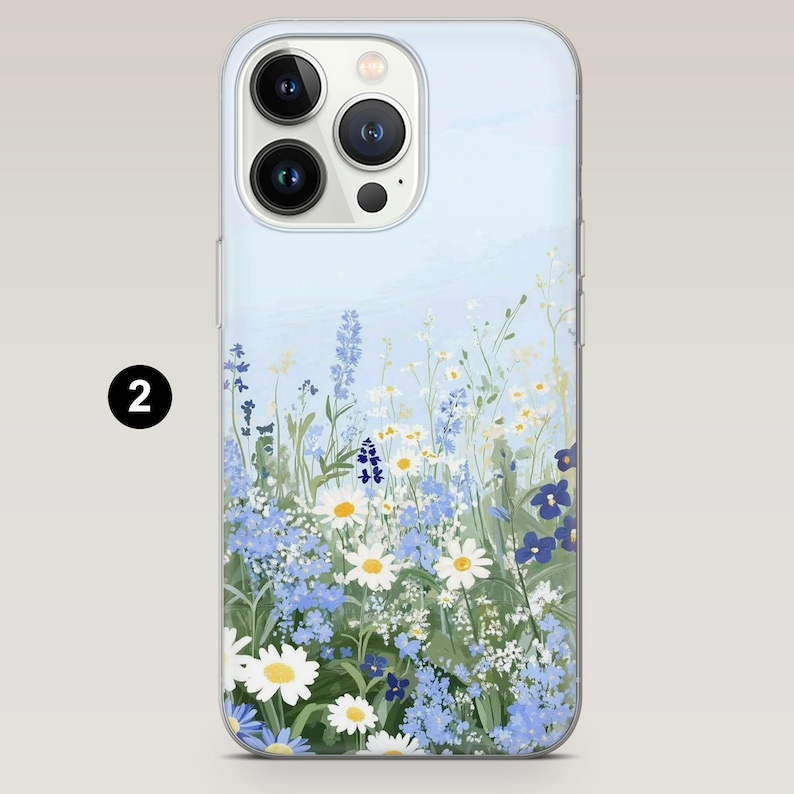 Op de afbeelding: Telefoonhoesje met een bloemenontwerp met witte madeliefjes, blauwe wilde bloemen en groen blad tegen een lichtblauwe achtergrond. De hoes heeft een transparante rand en een camera-uitsparing.