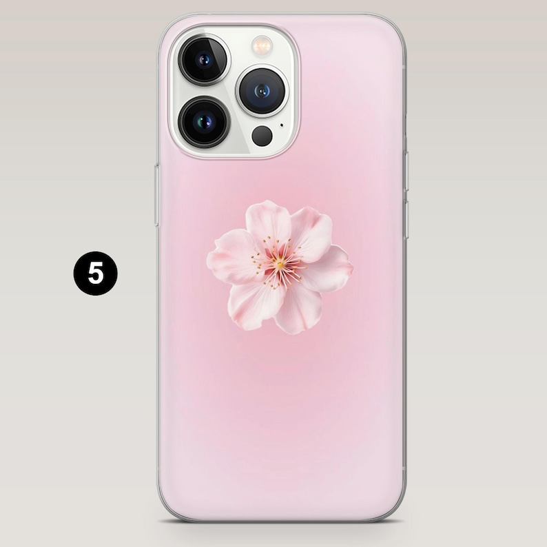 May include: A pink phone case featuring a delicate pink cherry blossom. The case has a smooth finish and a gradient background. The number "5" is in a black circle in the upper left corner.