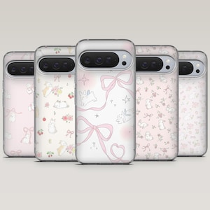 Pode incluir: Uma coleção de cinco capas de telemóvel com um esquema de cores rosa claro e branco. Cada capa apresenta um padrão diferente, incluindo coelhos, laços, estrelas e desenhos florais. As capas têm uma borda transparente e um recorte para a câmara.