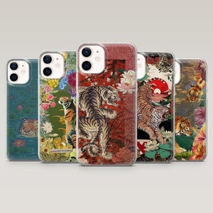May include: Five phone cases with unique designs. The cases feature illustrations of tigers, flowers, and Japanese-inspired art. The color palette includes shades of green, red, orange, and brown. The cases are made of clear plastic.
