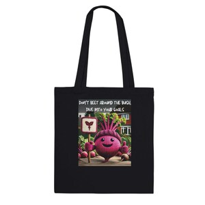 May include: Black tote bag with a pink beet character holding a sign that says "Don't beet around the bush. Dive into your goals."