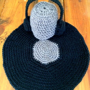 May include: A crocheted gray and black record with a gray crocheted hat on top. The record is black with a gray center and the hat has a gray crocheted headband.