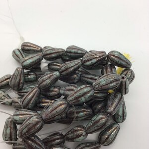 Peut inclure: Un brin de perles en verre turquoise et brun en forme de goutte. Les perles ont un aspect rustique et vieilli.