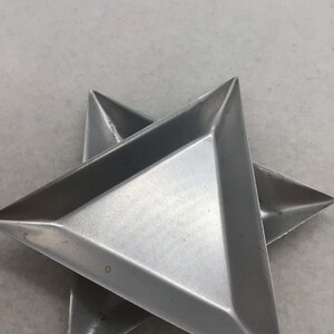 May include: Two silver-colored, star-shaped trays. Each tray is made of metal and has a triangular shape with raised edges. The trays are overlapping, with one slightly beneath the other.