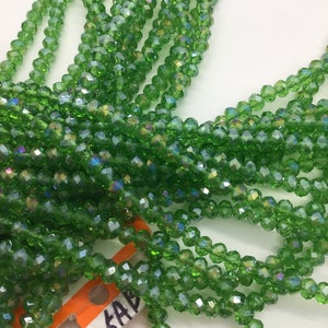 Peut inclure: Un brin de perles de verre facettées vertes. Les perles sont petites et ont un léger éclat iridescent. Les perles sont enfilées sur un fil transparent et sont prêtes à être utilisées pour la fabrication de bijoux.