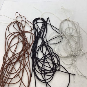 May include: Three bundles of thin, flexible wire in copper, black, and silver colors. Each bundle is loosely coiled and secured with a thin white string, creating a tangled appearance with multiple individual wire strands visible in each color group.