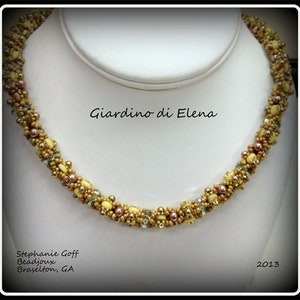 Puede incluir: Un collar de cuentas con un diseño en espiral, con cuentas doradas, marrones y crema. El collar se exhibe sobre un busto blanco. El texto "Giardino di Elena" está encima del collar. El texto "Stephanie Goff Beadjeux Braselton, GA" está debajo.