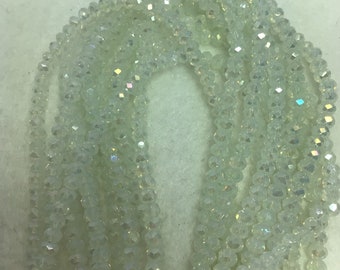 May include: A strand of iridescent white crystal beads. The beads are faceted and have a slight green tint.