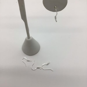 Puede incluir: Cuatro ganchos para pendientes de plata con cierre de resorte. Los ganchos se muestran sobre una superficie blanca.