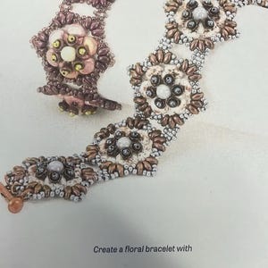 Könnte beinhalten: Ein Armband mit Perlen in einem floralen Design. Das Armband besteht aus braunen, weißen und silbernen Perlen. Das Armband ist aus Matubo- und Toho-Perlen gefertigt. Der Text "GINKGO BLOSSOMS" und "Design by Michelle Snyder" ist oben im Bild zu sehen. Der Text "Create a floral bracelet with MATUBO TOHO BEADS" ist unten im Bild zu sehen.