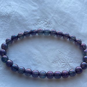 May include: A purple iridescent beaded bracelet with a sparkly finish.