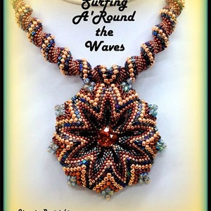 Könnte beinhalten: Eine Perlenkette mit einem großen, sternförmigen Anhänger. Die Kette besteht aus braunen, goldenen und blauen Perlen. Der Anhänger besteht aus den gleichen Perlen und hat eine dunkelbraune Mitte. Die Kette trägt den Titel "Surfing A'Round the Waves" und ist signiert mit "Jimmie Boatright 2013".