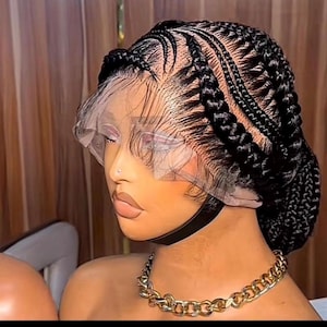May include: A black braided wig with a transparent lace front. The wig features intricate cornrow patterns and a bun at the back. A gold chain necklace is worn around the neck.