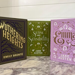 May include: Three hardcover books with floral designs on the covers. The books are titled "Wuthering Heights" by Emily Bront&euml;, "Sense and Sensibility" by Jane Austen, and "Emma" by Jane Austen.