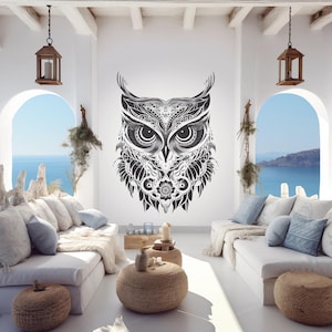 Könnte beinhalten: Ein detaillierter schwarz-weißer Eulen-Wandtattoo-Aufkleber dominiert einen hellen Raum. Das Eulen-Design weist komplizierte Muster und große Augen auf. Der Raum umfasst weiße Sofas, runde Couchtische und gewölbte Fenster mit Blick auf das Meer.