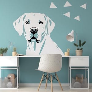 May include: A large white dog wall decal with black accents, set against a light blue wall. The dog's head and upper body are visible, with a detailed depiction of its eyes, nose, and mouth. White geometric triangles are above the dog.