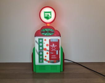 May include: A red, white, and green gas pump shaped like a vending machine with a light on top. The machine has a sign that says "Music Kick" and "Uno Mas!" with a red and white sombrero graphic.