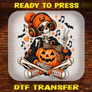May include: A DTF transfer print featuring a skeleton wearing an orange beanie with a jack-o'-lantern face, heart-shaped sunglasses, and headphones. The skeleton holds a pumpkin with a leopard print bow, wearing orange sneakers and making a peace sign.