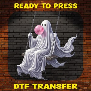 May include: A DTF transfer featuring a white ghost draped in a sheet, sitting on a wooden swing suspended by chains. The ghost is blowing a large pink bubble with bubblegum. The text READY TO PRESS and DTF TRANSFER appears in yellow letters.