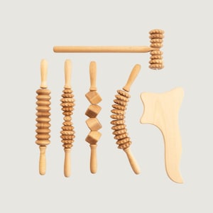 Può includere: Un set di sei strumenti per massaggio in legno chiaro che include quattro rulli manuali con varie texture, un rullo a forma di martello e uno strumento di raschiatura curvo e liscio. Ogni pezzo presenta una finitura in legno naturale e manici lisci.