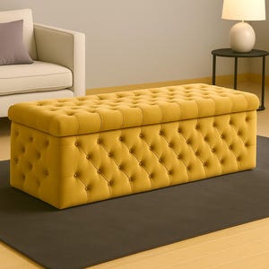May include: A mustard-yellow rectangular storage ottoman with a buttoned, tufted design. The top and sides are covered in fabric, and the tufting is accented with buttons. The ottoman sits on a dark grey rug.