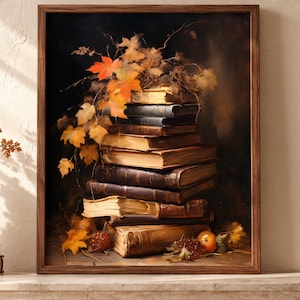 Op de afbeelding: Een ingelijst schilderij met een verticale stapel oude, in leer gebonden boeken op een ondergrond. Feloranje en gele herfst-esdoornbladeren hangen over de bovenkant van de boeken, vergezeld door kleine rode bessen en een enkele oranje vrucht.