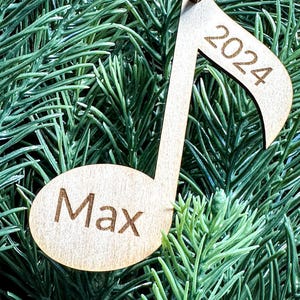 Puede incluir: Un adorno de madera en forma de nota musical con el año 2024 y el nombre Max grabado.