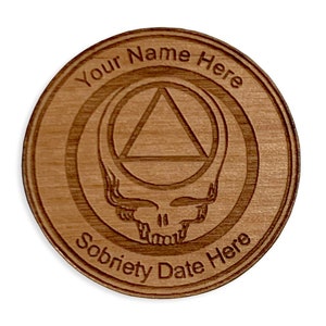 May include: A wooden coin with a carved design of a triangle inside a circle, a skull, and the text "Your Name Here" and "Sobriety Date Here".
