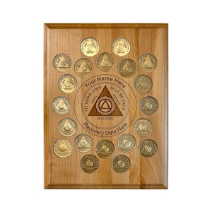 May include: A wooden plaque with a circle of gold coins, each with a different number of years of sobriety. The center of the plaque has a triangle with the words "To Thine Own Self Be True" and "Recovery".