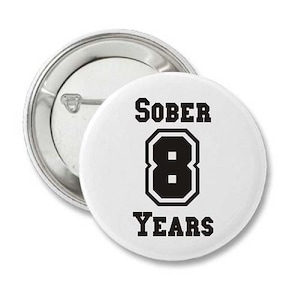 May include: White button with black text that reads "SOBER 8 YEARS". The number 8 is in a large, bold font.