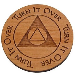 May include: A wooden coin with a triangle design and the text "Turn it over" repeated four times around the edge.