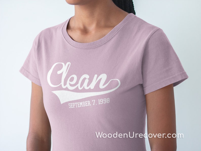 May include: A light pink t-shirt with the word "Clean" in white text with a white baseball-style arc underneath. The text "SEPTEMBER 7, 1990" is below the arc.