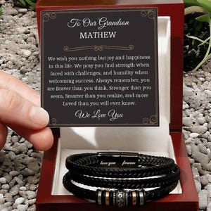 May include: A black leather bracelet set in a red wooden box. The bracelet features a metal clasp engraved with "love you forever." A card inside the box reads "To Our Grandson MATHEW" and a loving message.