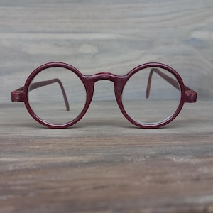 May include: A pair of round, burgundy-colored eyeglasses with clear lenses.