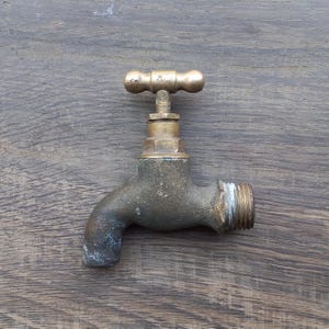 May include: A brass outdoor faucet with a T-shaped handle. The faucet is weathered and has a worn finish.