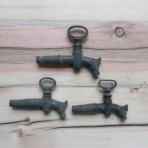 Könnte beinhalten: Drei antike Bronzemündungen mit einem dekorativen Design. Die Mündungen befinden sich auf einer Holzoberfläche.